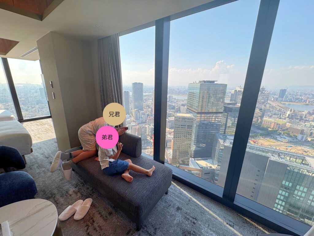 大阪の街並みを背景に、ソファでくつろぐ子どもたち。