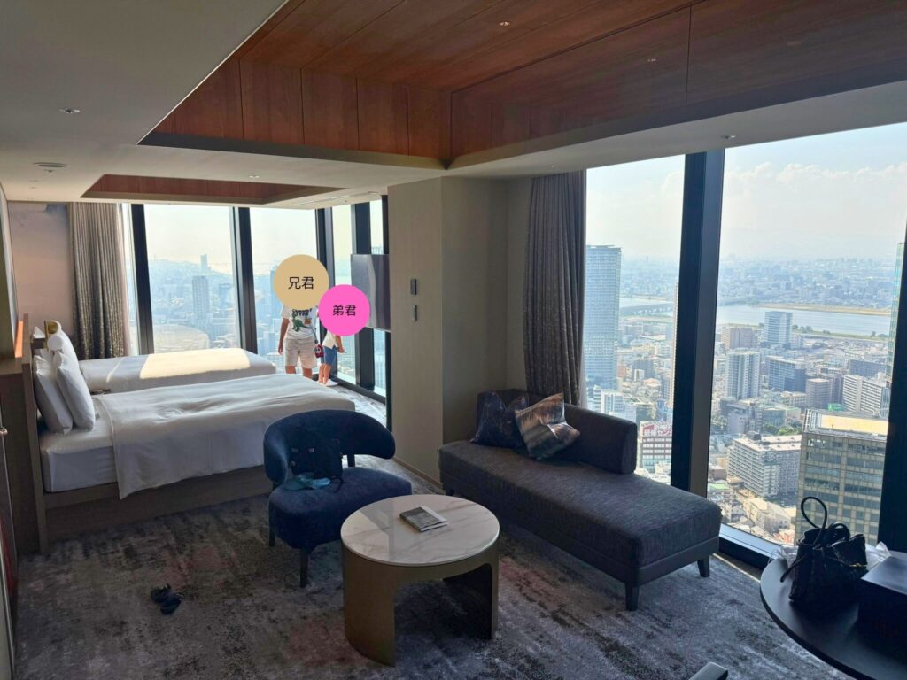 大阪ステーションホテルのスペシャリティ コーナーツイン客室全景。ベッドとソファが配置された広々とした室内。