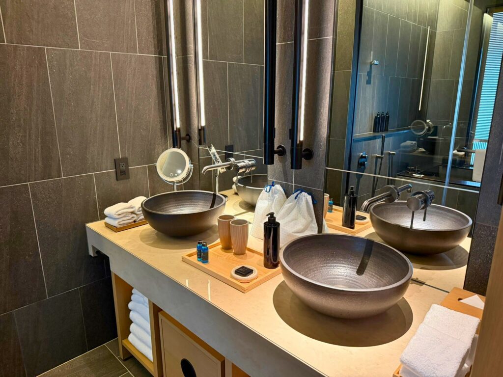 ROKU京都の洗面エリア。信楽焼のボウル型洗面台と木のトレイが上品に配置されたモダンなデザイン。