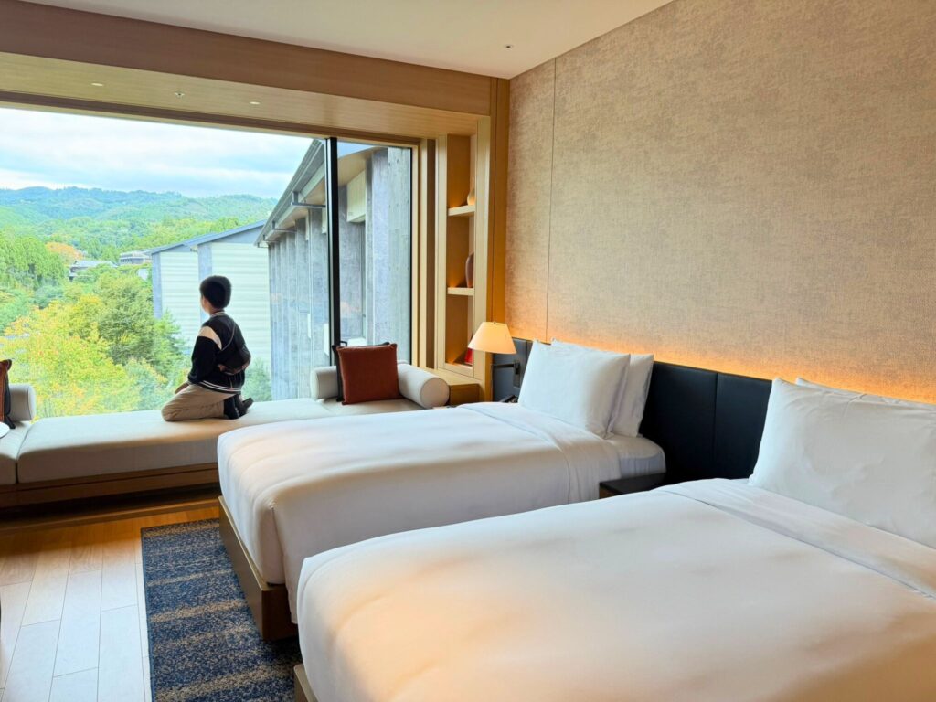 ROKU京都のツインルームからの眺望。大きな窓から京都北山の緑を望む、開放感あふれる客室。