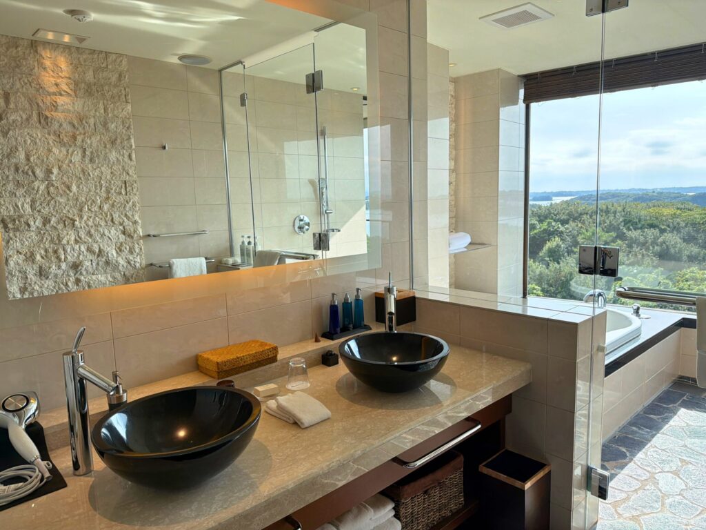 志摩観光ホテル ザ・ベイスイートの洗面台。ダブルボウルの広いカウンターと高級感のあるバスエリア。