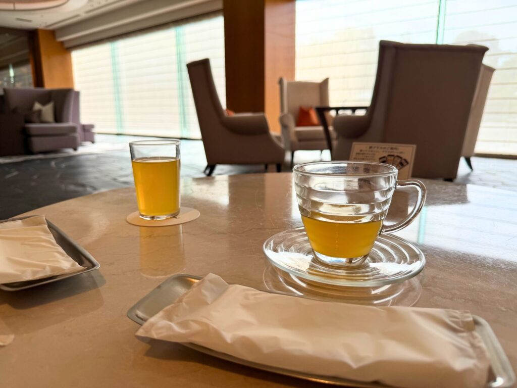 志摩観光ホテル ザ・ベイスイートのロビーで提供されるウェルカムドリンク。明るい空間でゆったりチェックインできる様子。