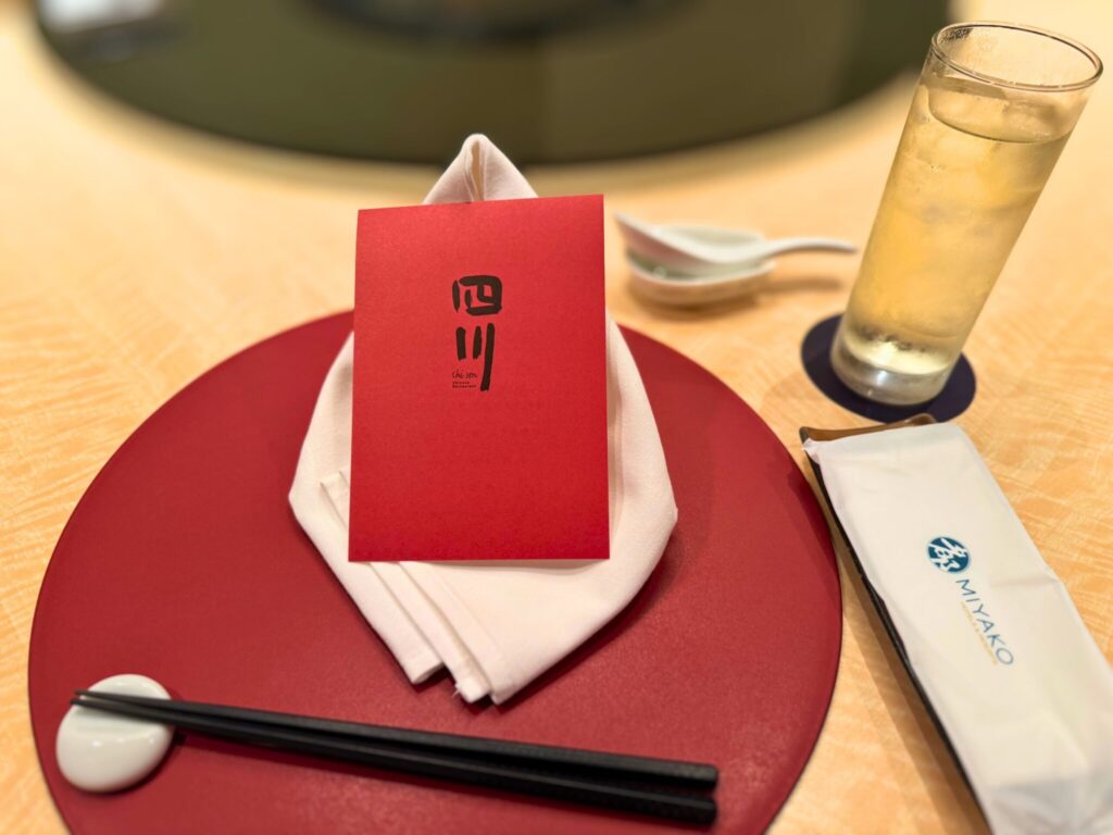 都ホテル四日市「四川」ディナーのテーブルセッティング。赤いメニューカードと白いクロスが印象的