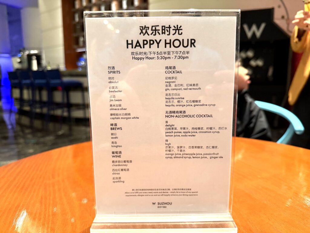 W蘇州ホテルのハッピーアワーのメニュー表。スピリッツ・ビール・ワイン・カクテル・ノンアルコールカクテルの種類が英語と中国語で掲載されている(17:30〜19:30)
