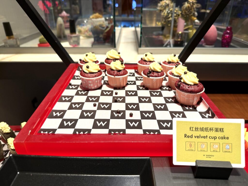 W蘇州ホテルのハッピーアワーデザート。Wロゴのトレイに並んだレッドベルベットカップケーキにバニラクリームがトッピングされている